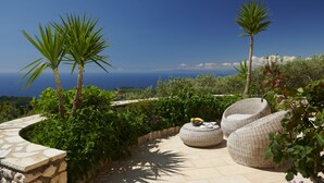 Un patio con mobiliario de mimbre y vistas al mar.