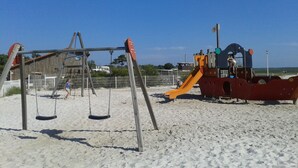 Een strand speeltuin met schommels en een glijbaan.