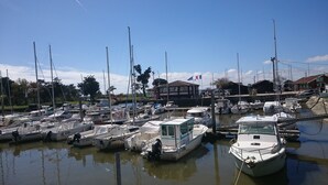 Een jachthaven met verschillende boten afgemeerd, een gebouw met een vlag en een heldere lucht.