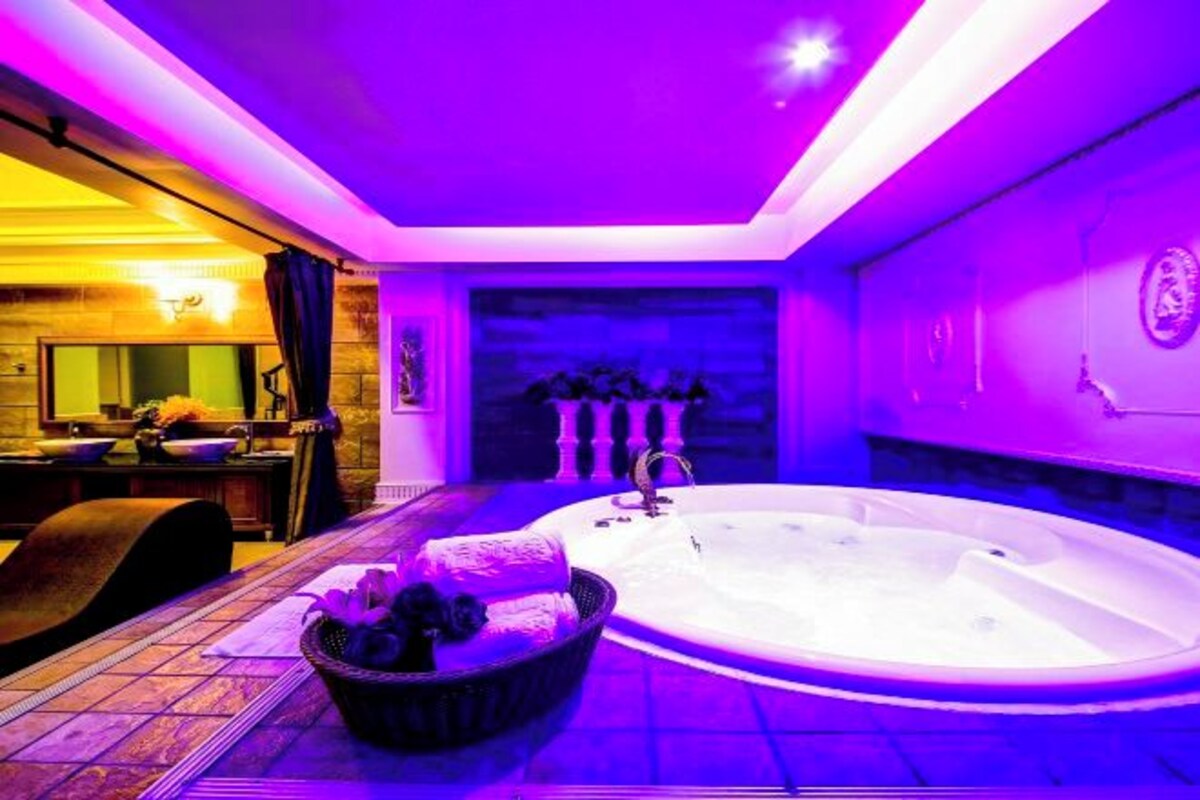 A modern bathroom with a large bathtub, a sink, and a dining area with a table and chairs.