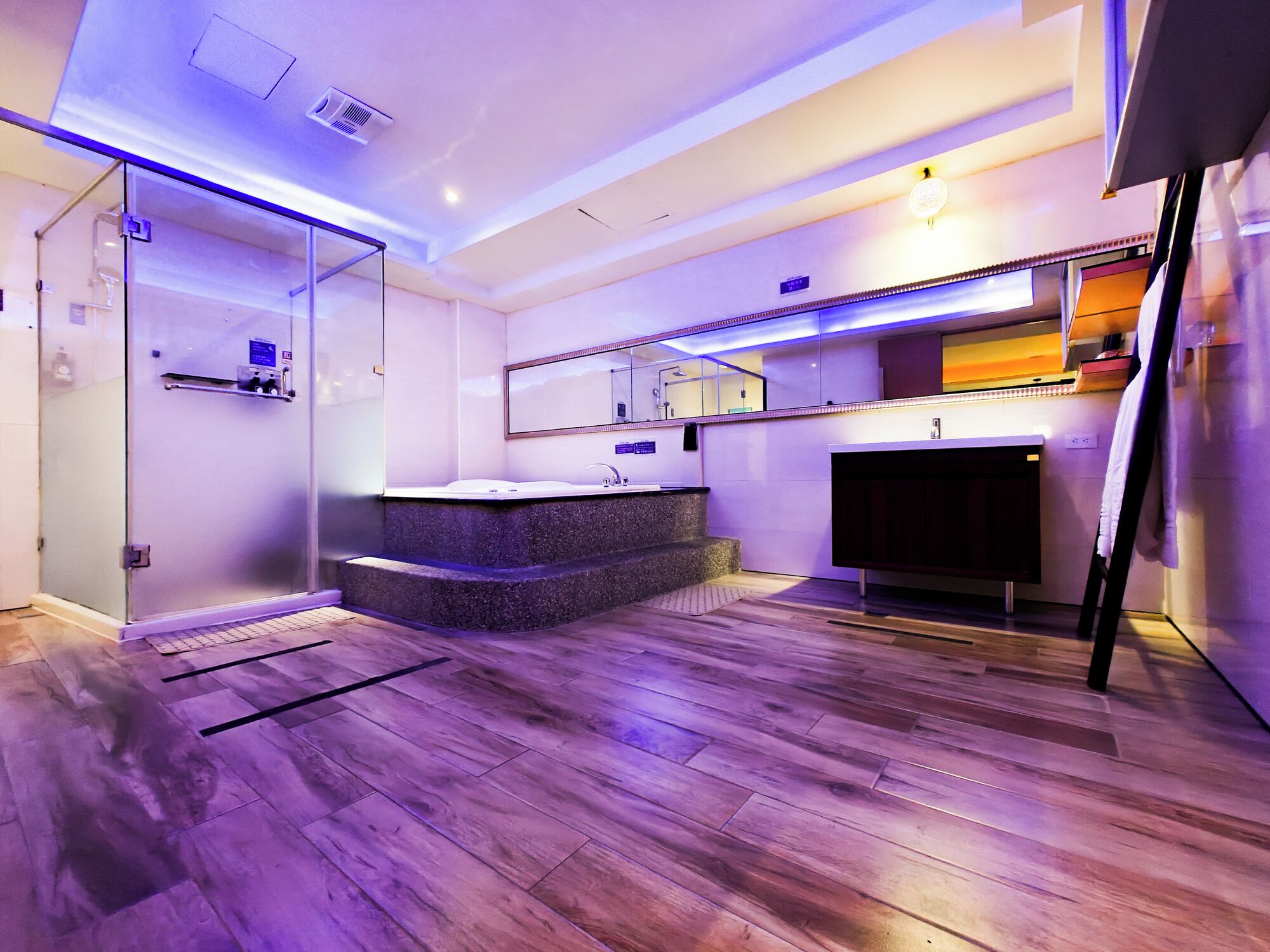 A modern bathroom with a glass shower enclosure, a granite countertop sink, and a mirror above it.