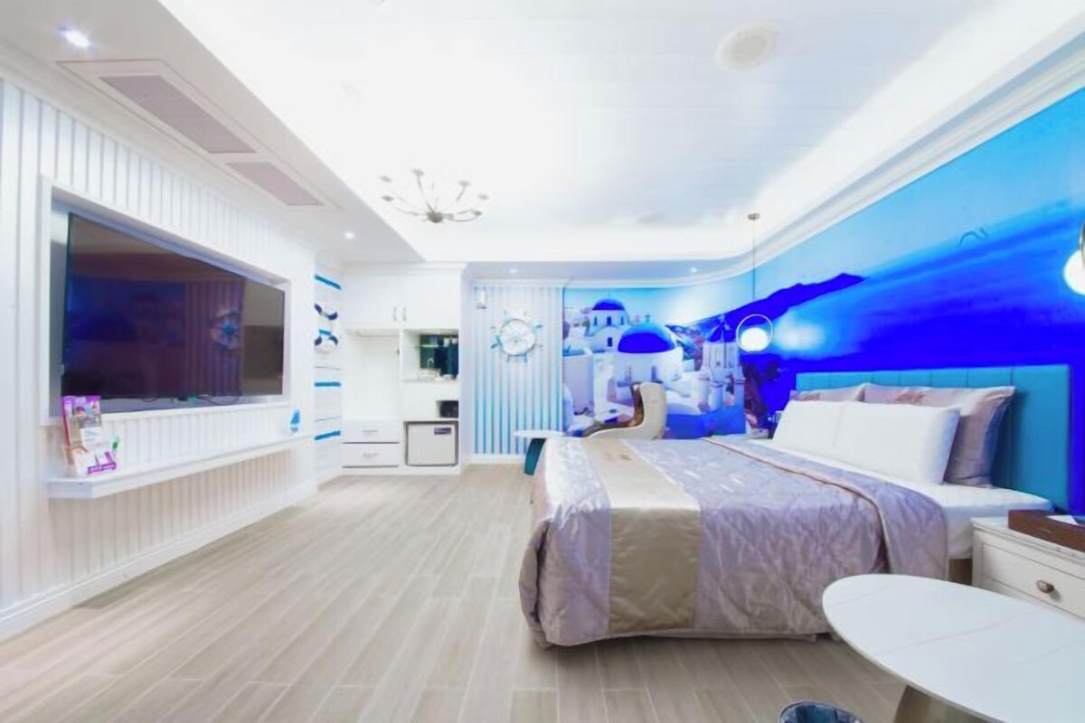 A modern bedroom with a large bed, bedside tables, and a TV.