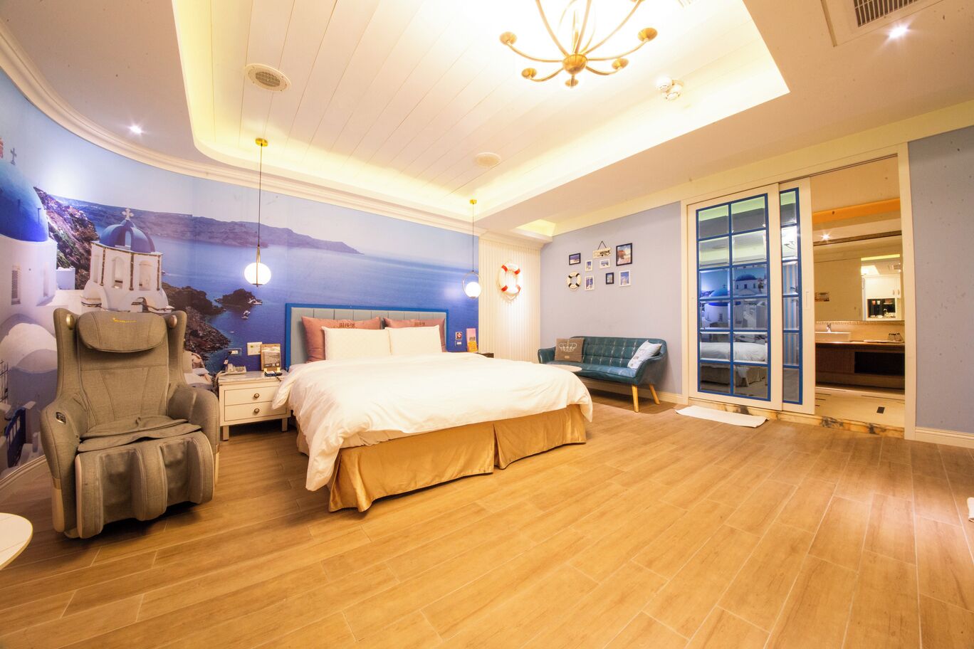 Un dormitorio con una cama grande, un sillón de masaje, un sofá y una puerta corrediza de vidrio que da al baño.