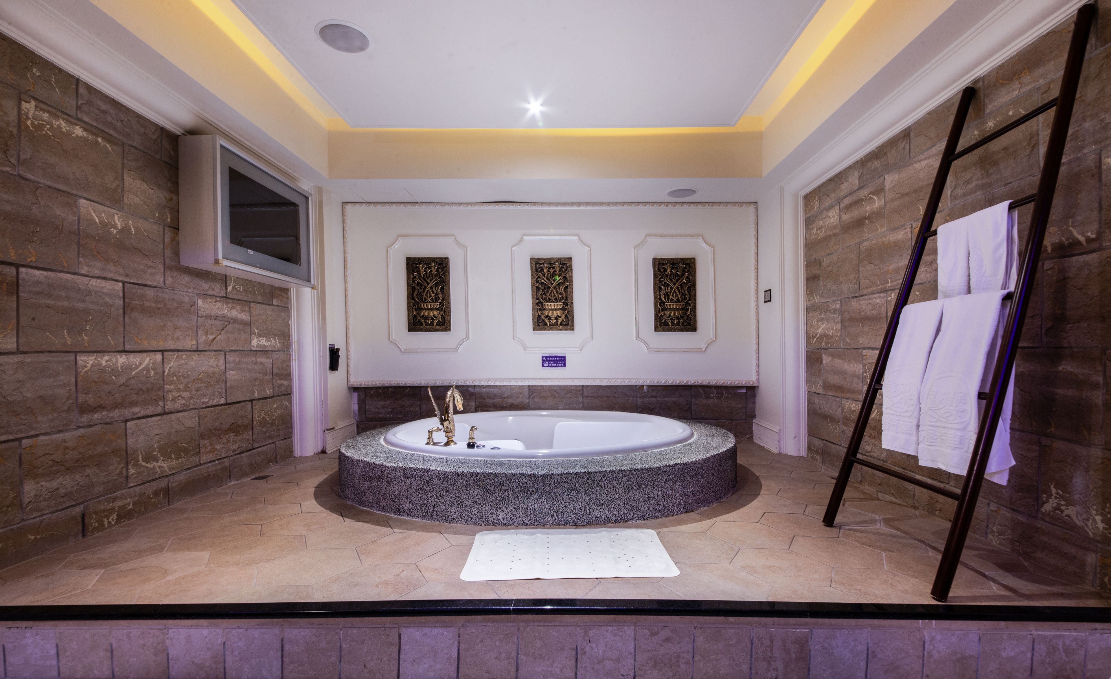 A bathroom with a freestanding bathtub, stone walls, and a towel rack.