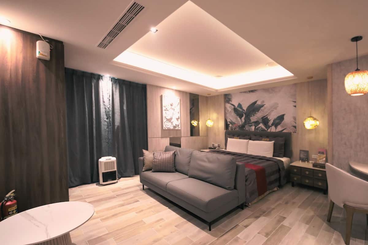 Una habitación de hotel moderna con sofá, cama, escritorio y un espejo grande.