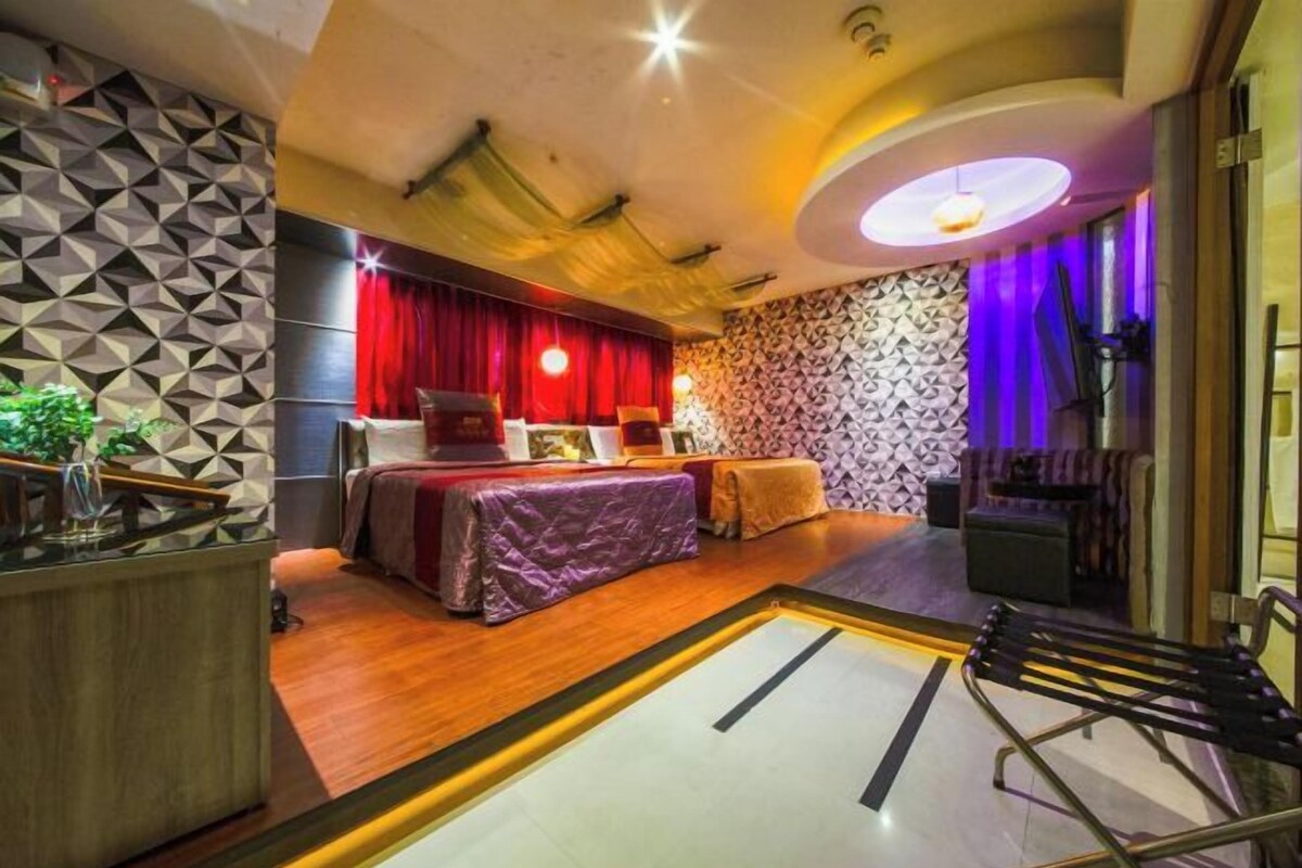 A modern hotel room with a bed, a desk, and a seating area.