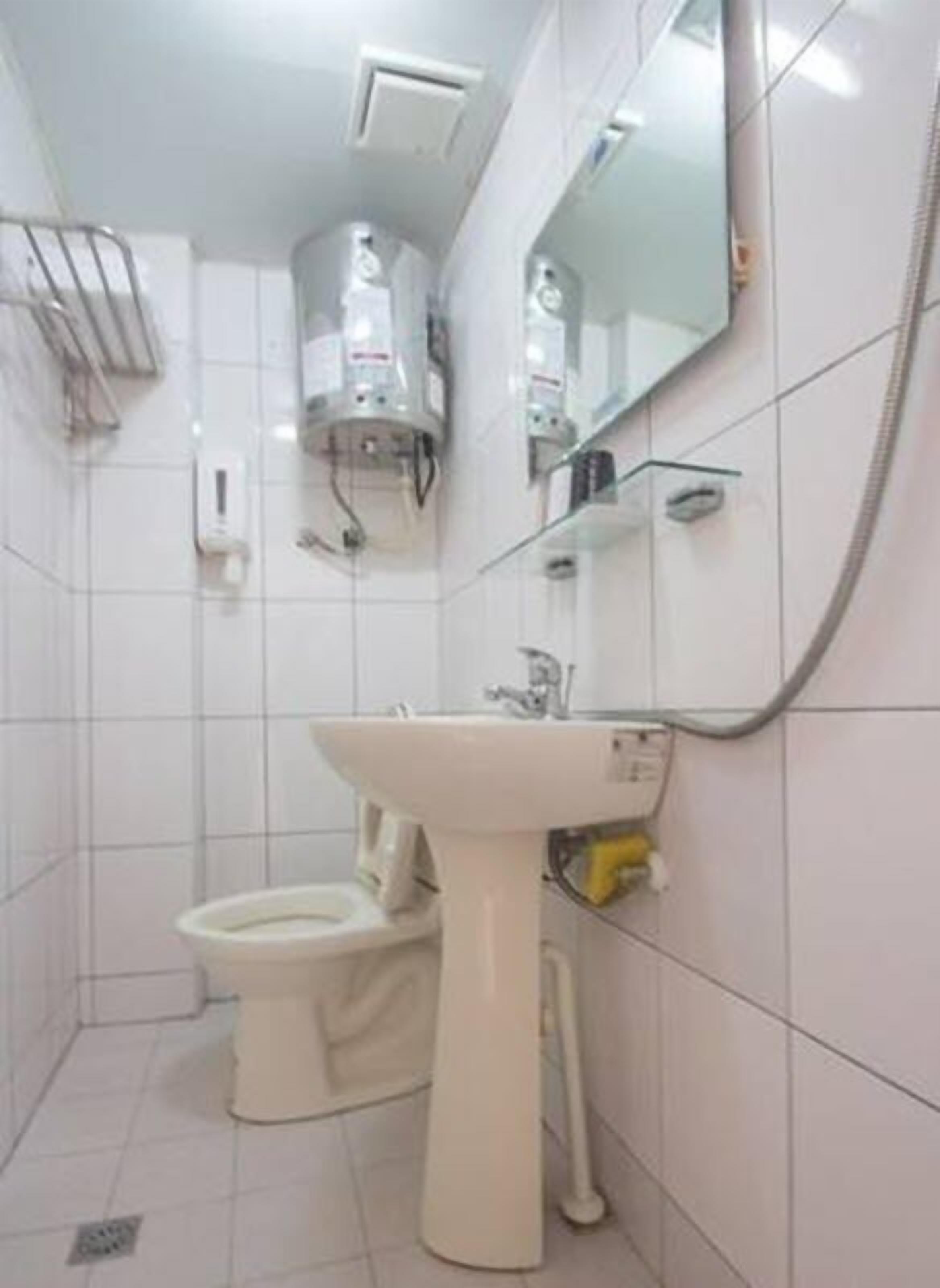 A small, clean bathroom with a toilet, sink, and a mirror.