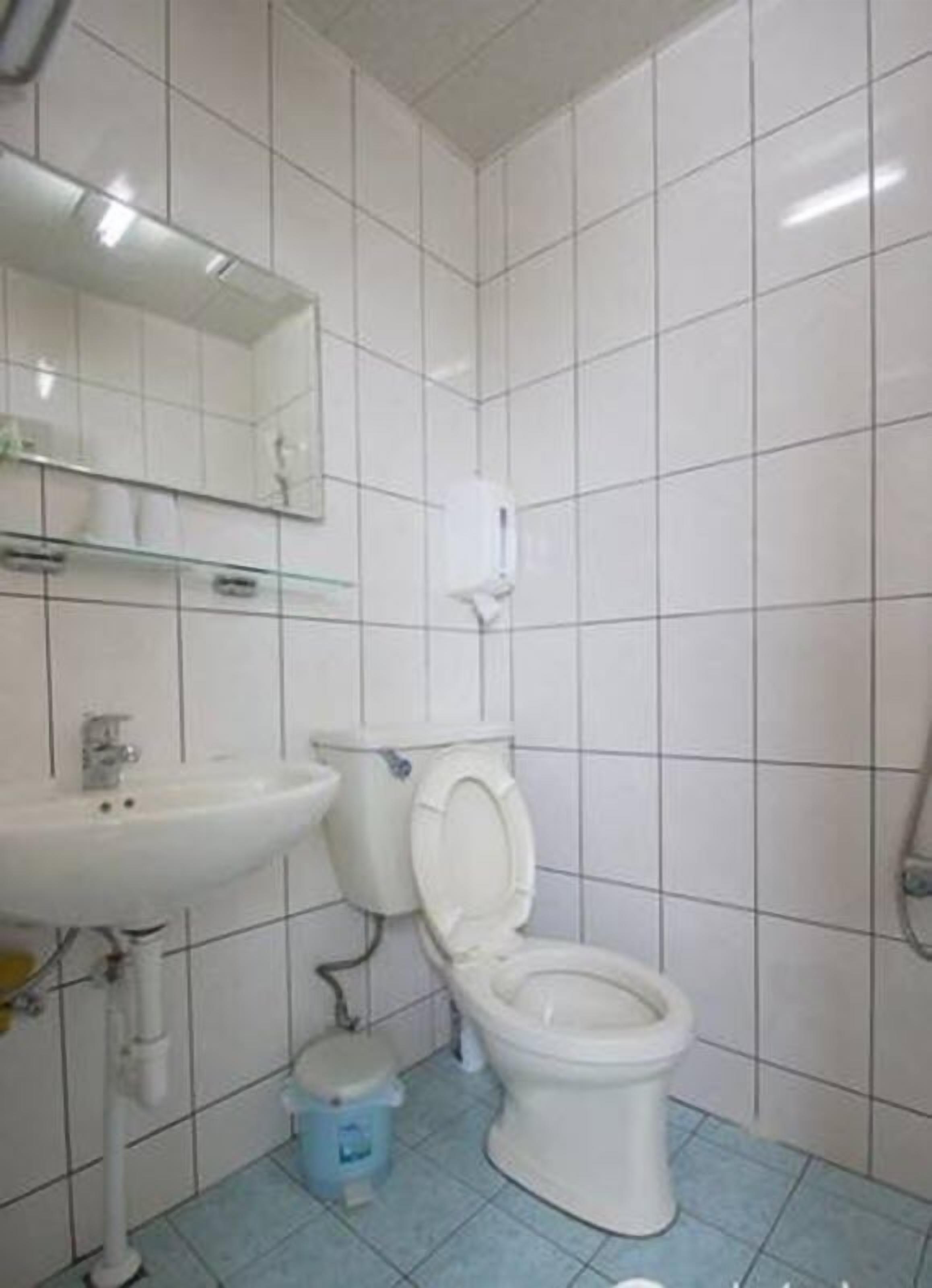Un baño con azulejos blancos, un lavabo, un inodoro y un espejo.