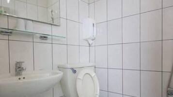 Un baño con azulejos blancos, un lavabo, un inodoro y un espejo.