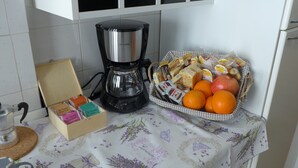 A kitchen with a coffee maker, a basket of fruits and snacks, and a box of tea bags. - Your Home @ ROME near TRASTEVERE (Roma)