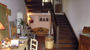 Una sala acogedora con una escalera de madera, una mesa de comedor con sillas y un sofá.