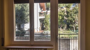 A window with a view of a building, a fence, and trees. - S034 - Sirolo, tastefully furnished four-room apartment in the center (Sirolo)