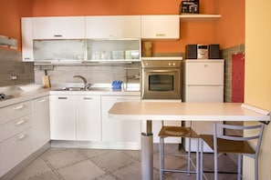 A modern kitchen with white cabinets, a stainless steel oven, and a small refrigerator.