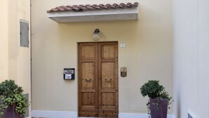 A wooden double door with a light fixture above it, a small sign with the number 3, and two potted plants on either side. - S034 - Sirolo, tastefully furnished four-room apartment in the center (Sirolo)