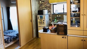 A compact kitchen with wooden cabinets, a microwave, and a small refrigerator.