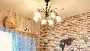 A cozy room with a brick wall, a world map mural, a black sofa, a wooden coffee table, and a patterned chair.