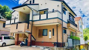 A two-story building with a flat roof and a balcony on the upper floor.