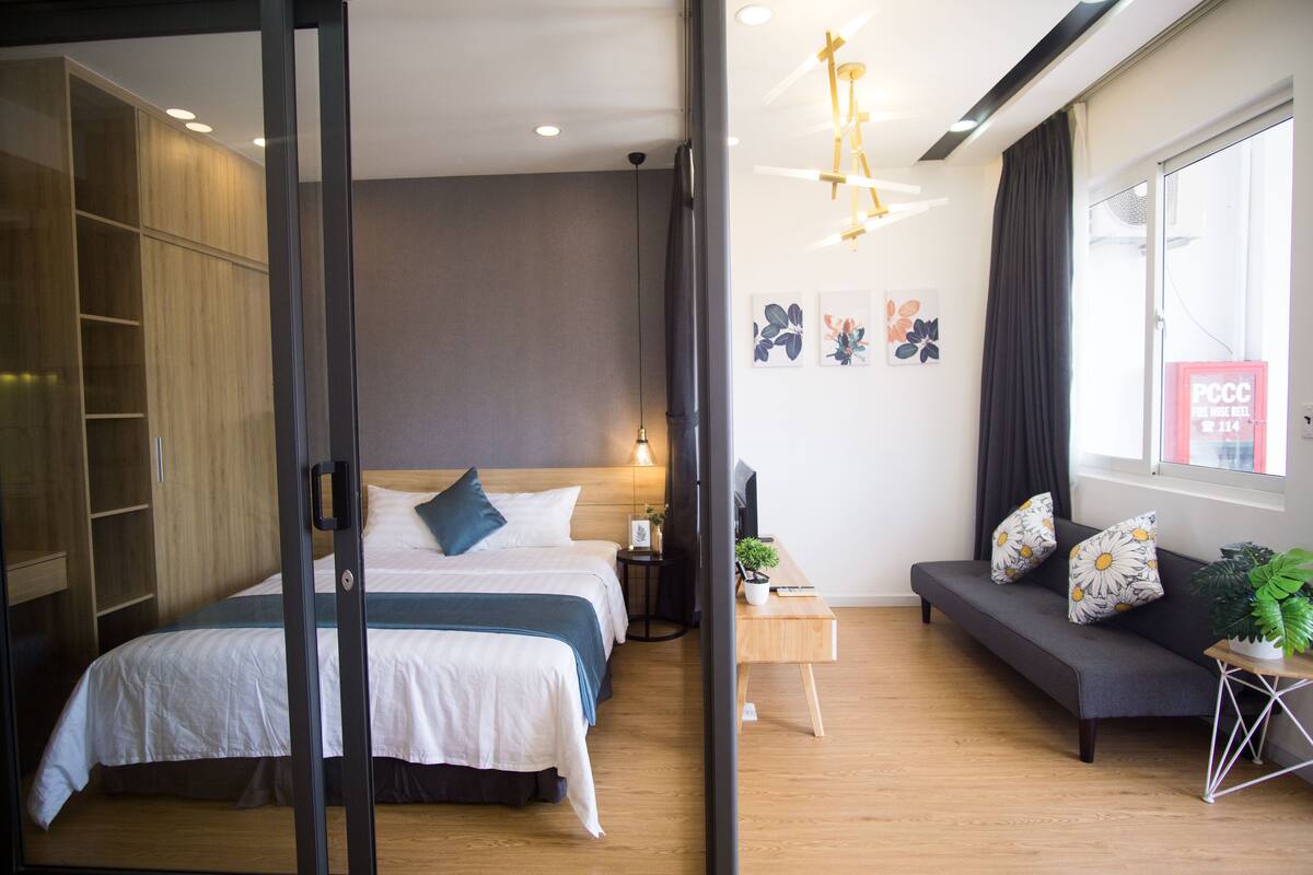 A modern bedroom with a bed, bedside table, and a sofa.