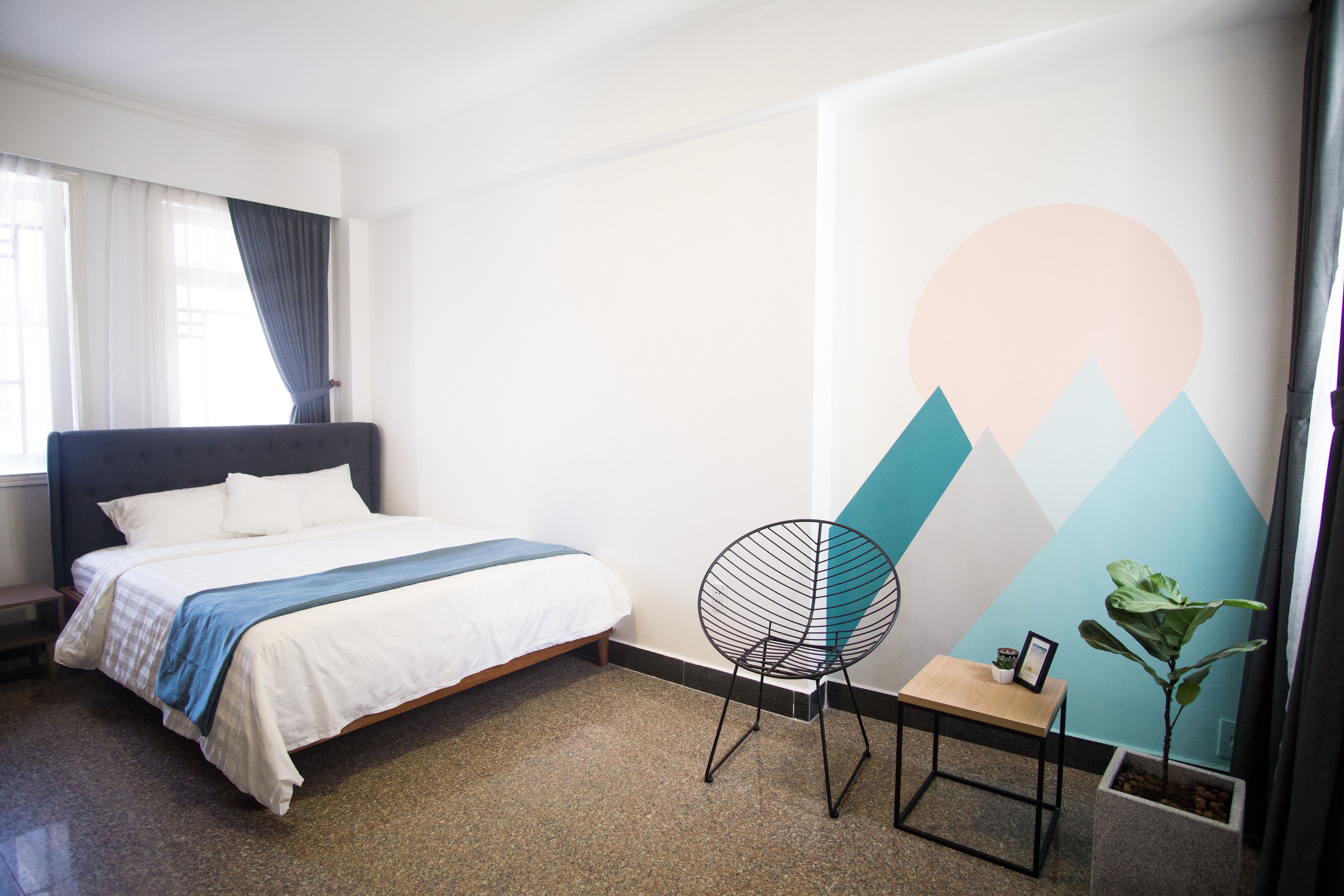 Ein Schlafzimmer mit einem Bett, einem Sessel, einem kleinen Tisch und einer Wand mit geometrischem Muster.