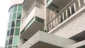 A hotel with a modern design, featuring a prominent balcony with metal railings and a large glass window on the upper floor. - Cuu Kim Son Hotel (Ho Chi Minh City)