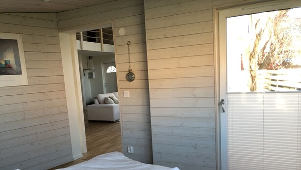 Een slaapkamer met een bed, een schuifdeur naar een balkon en uitzicht op de omgeving.