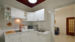 A compact kitchen with white cabinets, a built-in oven, a sink, and a toaster.
