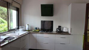 Une cuisine moderne avec des meubles blancs, une fenêtre et un meuble vert placé au-dessus de la cuisinière.