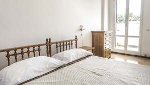 A bedroom with a wooden bed, white bedding, a wooden dresser, and a door leading to a balcony. - M051 - Marcelli, villa with garden 200 meters from the sea (Marcelli)