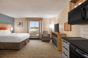 A hotel room with a bed, a chair, a TV, a microwave, and a dresser. - Candlewood Suites Augusta (Augusta)