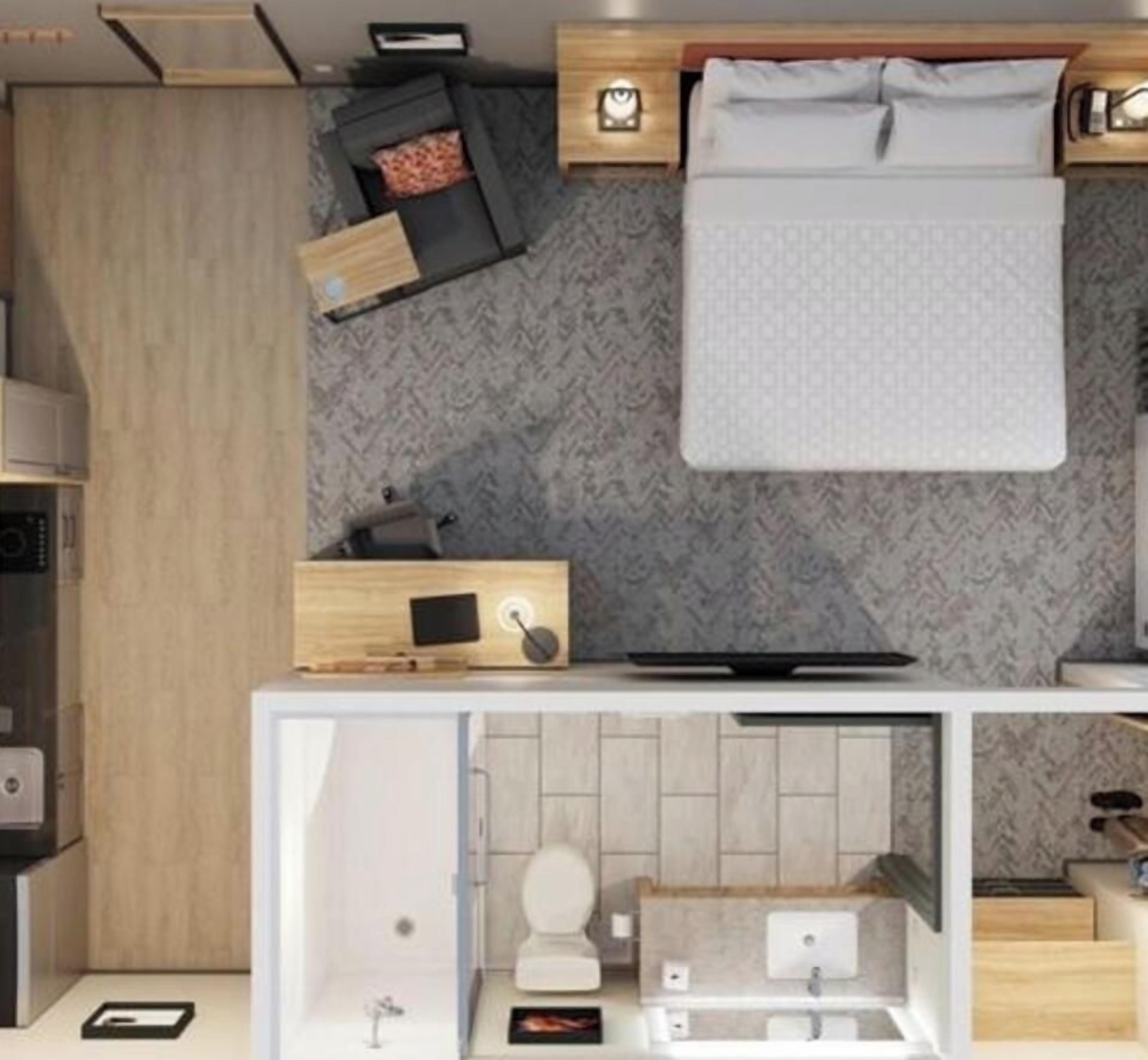 Une chambre d’hôtel de taille réduite, comprenant un lit, une table de chevet et une petite salle de bain avec des toilettes et un lavabo.