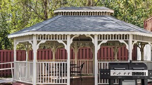 A gazebo with a dark roof and white trim, featuring a grill and outdoor seating. - Candlewood Suites Augusta (Augusta)