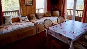 A cozy cabin room with a wooden interior, a bed with a quilted bedspread, a table with a tablecloth, and a television mounted on the wall. - Apartment/ flat - Courchevel 1850 (Courchevel)