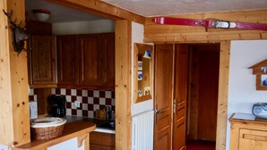 A wooden kitchen with a checkered backsplash, wooden cabinets, a red carpeted hallway, and a mounted deer head. - Apartment/ flat - Courchevel 1850 (Courchevel)