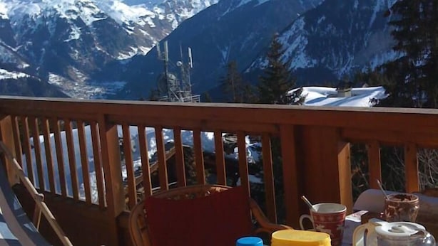 A table set outdoors with a mountain view, including a bottle, mug, and food items. - Apartment/ flat - Courchevel 1850 (Courchevel)
