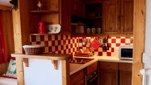 A compact kitchen with wooden cabinets, a microwave, and a checkered backsplash. - Apartment/ flat - Courchevel 1850 (Courchevel)