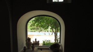 A small arched window with a view of a swimming pool and greenery outside. - Cas Bunyoler - In Cas Concos, Felanitx, with private swimming pool, AC bedrooms (Cas Concos des Cavaller)