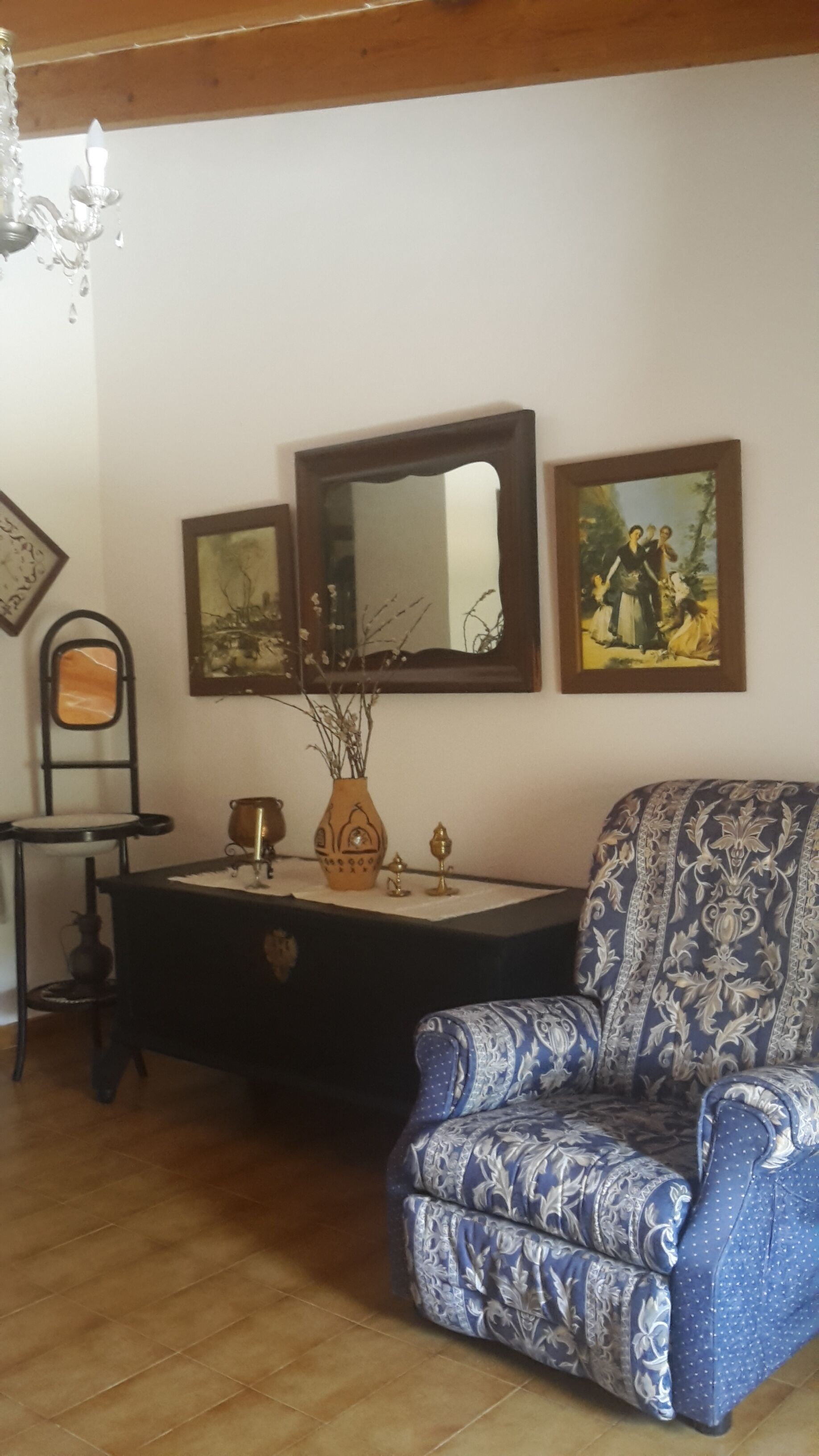 Une pièce comprenant un fauteuil à motifs, une commode, un miroir et un tableau accroché au mur.