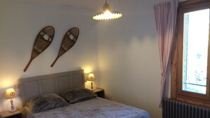Ein Schlafzimmer mit einem Bett, zwei Wandkörben, einem Fenster mit Vorhängen und einer Heizung.