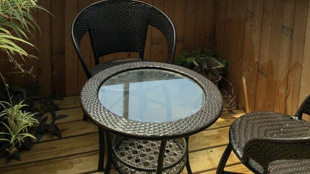 A corner room with a view of the sea, a round table, two wicker chairs, and wooden walls. - Wefun Inn (Jinning)