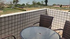 A balcony with a round glass table and wicker chairs, overlooking a body of water with distant cityscape and bridge. - Wefun Inn (Jinning)