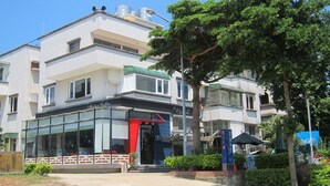 A building with a coffee shop on the ground floor, multiple floors, and a tree in front. - Wefun Inn (Jinning)