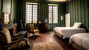 Une chambre avec deux lits, une chaise, une commode et un miroir.