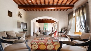 A spacious living room with a high wooden ceiling, a central coffee table, and a sofa. - Villa just 14 km to Florence, 8 bedrooms. Garden, private pool and Wi-Fi! (Rignano sull'Arno)