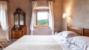 A bedroom with a large bed, a wooden dresser, a mirror, a window with curtains, and a lamp. - Villa just 14 km to Florence, 8 bedrooms. Garden, private pool and Wi-Fi! (Rignano sull'Arno)
