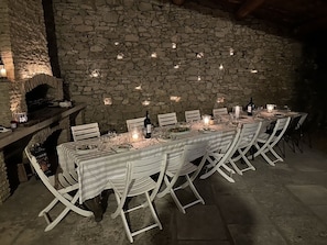 An outdoor dining area with a stone wall backdrop, a built-in oven, and white striped tablecloths.