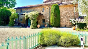A stone building with a tiled roof, a wooden fence, and a well-maintained garden.