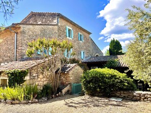 A stone building with a tiled roof, a green door, and a gravel pathway.