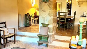 A rustic interior with a stone archway, wooden furniture, and a tiled floor.