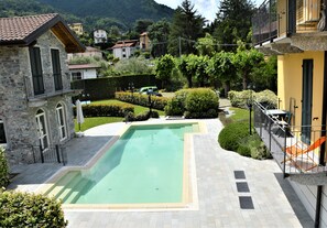 A courtyard with a swimming pool, stone buildings, and a green landscape.