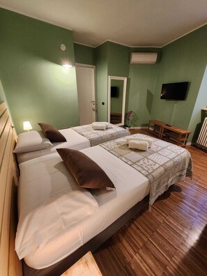 A bedroom with two beds, a television, a mirror, and a small table.